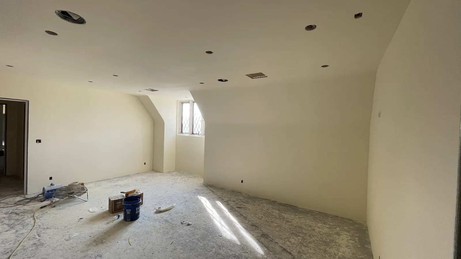 A room skim-coated smooth, ceiling and walls reading as one continuous plane with no visible seams or fastener lines.