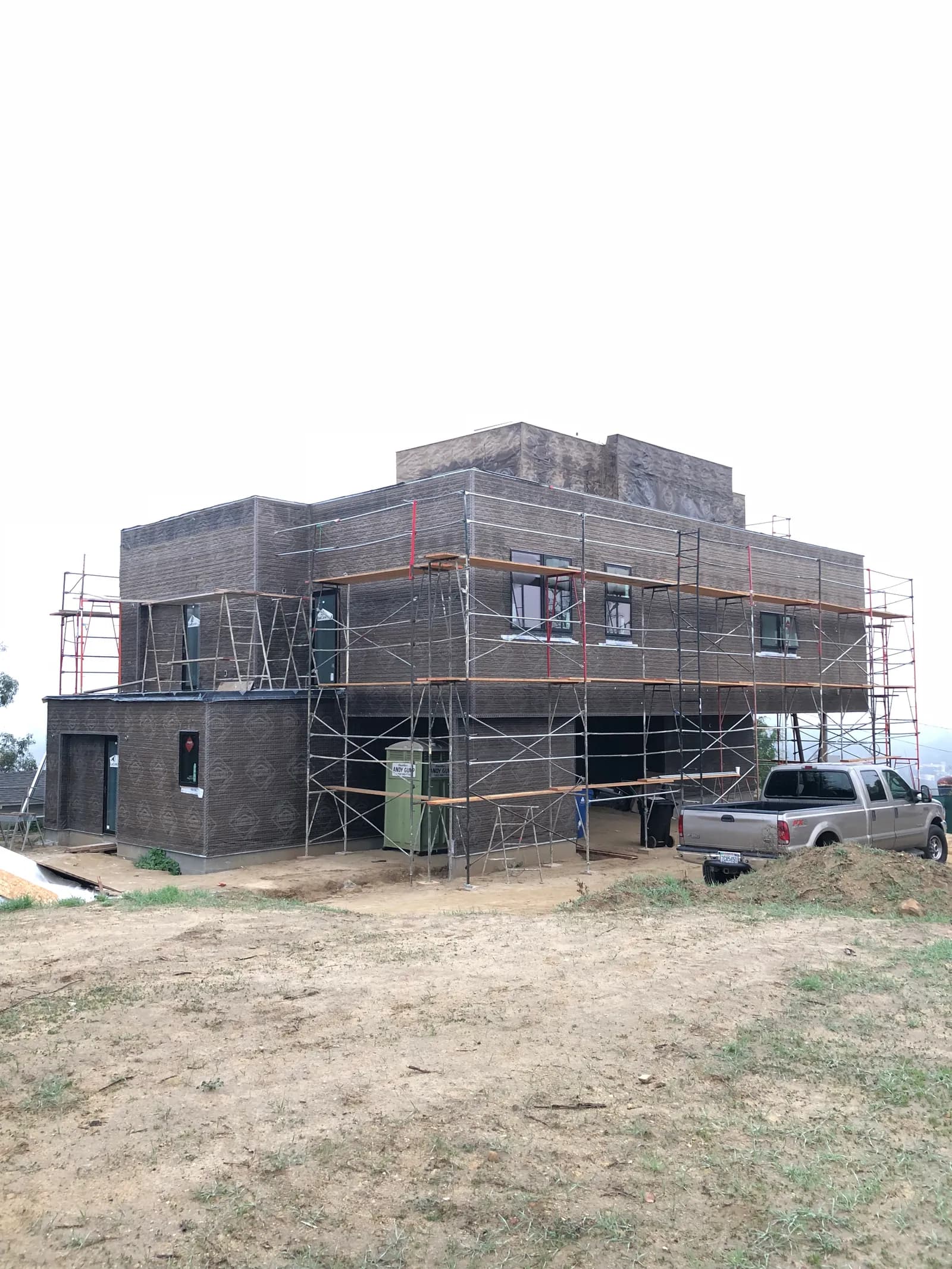 The exterior of the Silver Lake house mid-construction, wrapped and scaffolded on a hillside lot.